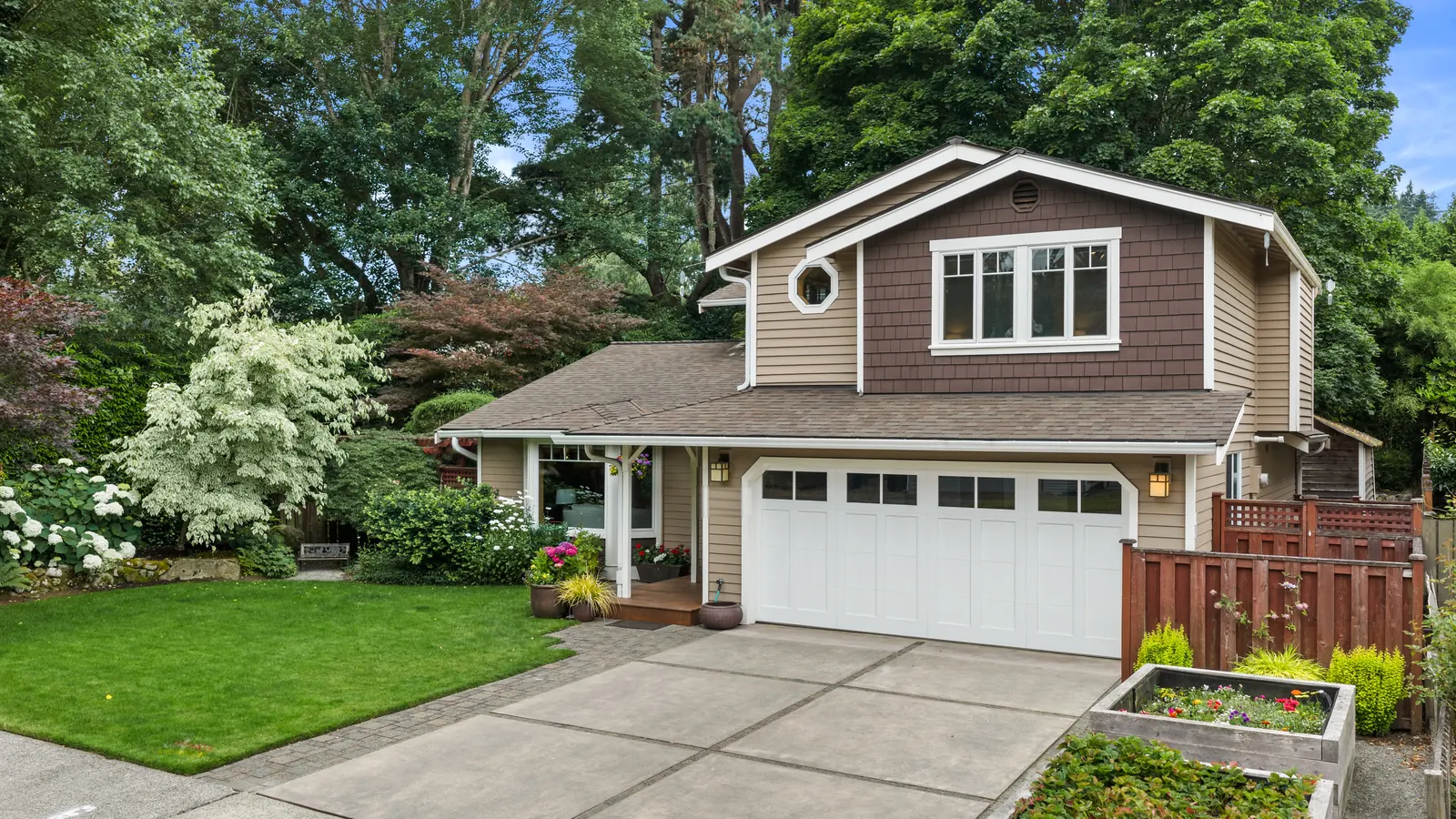 Drone view of a two-story craftsman home with a garden and garage